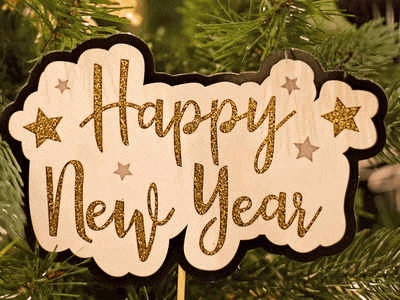 a sign that says `` happy new year '' is hanging on a christmas tree .