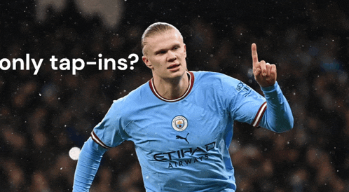 a soccer player wearing a blue etihad airways jersey points up