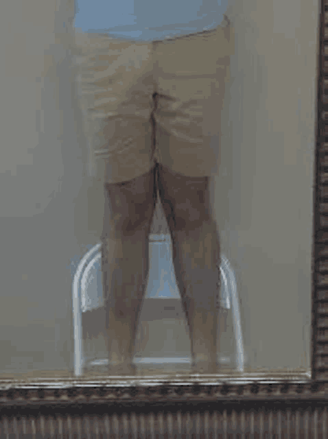 a person is standing in front of a mirror with their legs crossed .