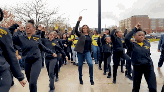 a woman in a black jacket is leading a group of people wearing black sweatshirts with the word chicago on them