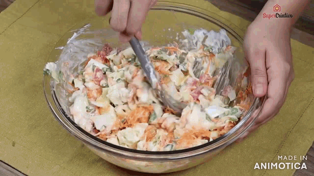 a person is mixing a salad in a glass bowl with the words made in animatica written on the bottom