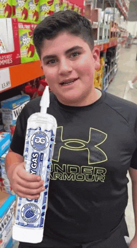 a boy wearing a black under armour shirt is holding a bottle of oxy gas