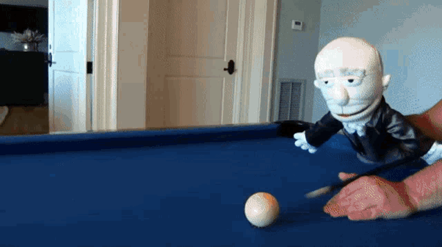 a puppet is playing pool with a cue and a ball