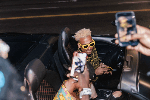 a man wearing yellow sunglasses is being photographed by a group of people