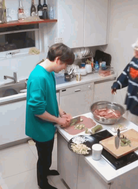 a man in a green shirt is cutting vegetables in a kitchen with a sign that says chains on it