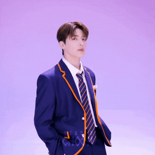 a young man in a blue suit and tie is standing in front of a purple background that says studio choo