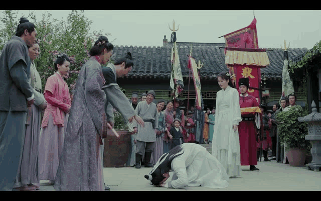 a man kneeling down in front of a group of people with a banner with chinese characters on it