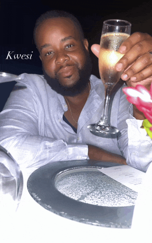 a man is holding a glass of champagne with the word kwesi written on the bottom