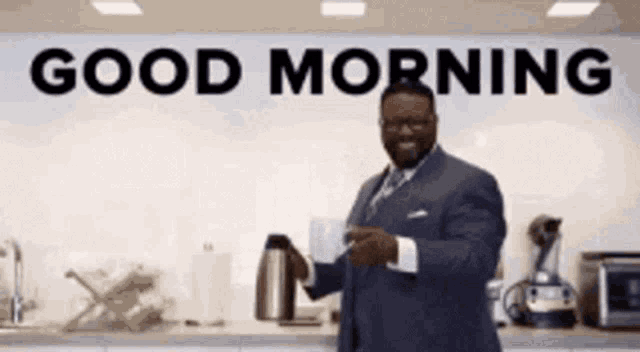 a man in a suit is holding a cup of coffee in front of a sign that says good morning .