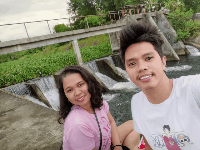 a man and a woman are posing for a picture and the man is wearing a shirt that says one piece