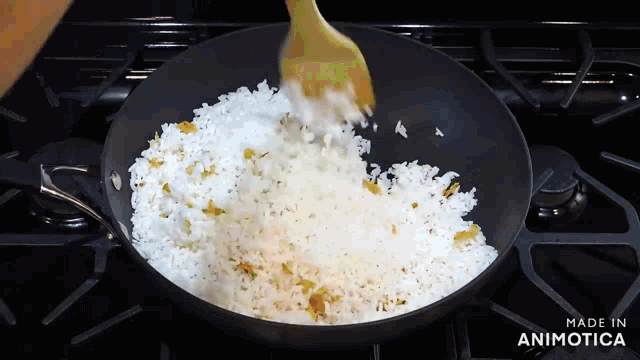 a pan of rice is being stirred with a wooden spoon and the words made in animatica are visible on the stove