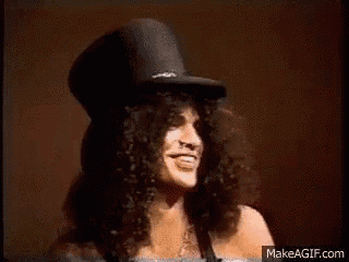 a man with long curly hair and a top hat is smiling .