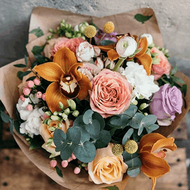 a bouquet of flowers wrapped in brown paper is sitting on a table