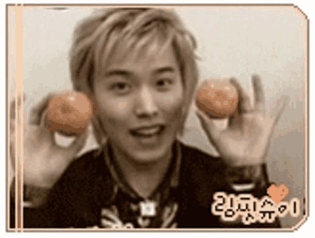 a young man is holding two oranges in front of his face