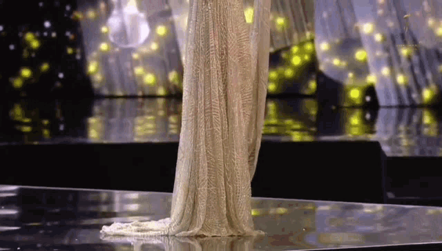 a woman in a long dress is walking down a runway .