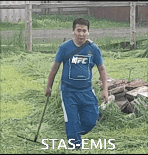 a man wearing a kfc shirt is walking through a grassy field