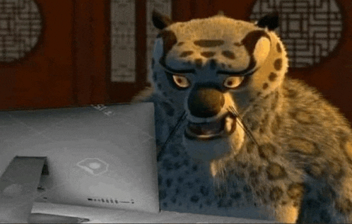 a leopard is sitting in front of a laptop computer .