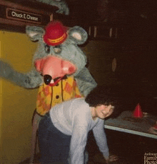 a chuck e cheese mascot stands next to a woman