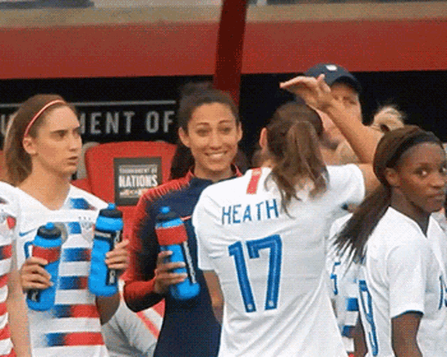 a group of female soccer players are standing in front of a sign that says " tournament of nations "