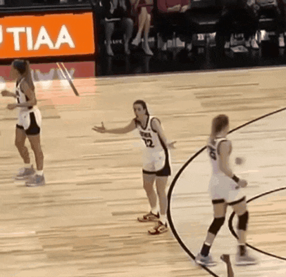 a group of women are playing basketball on a court with a sign that says tiaa in the background .