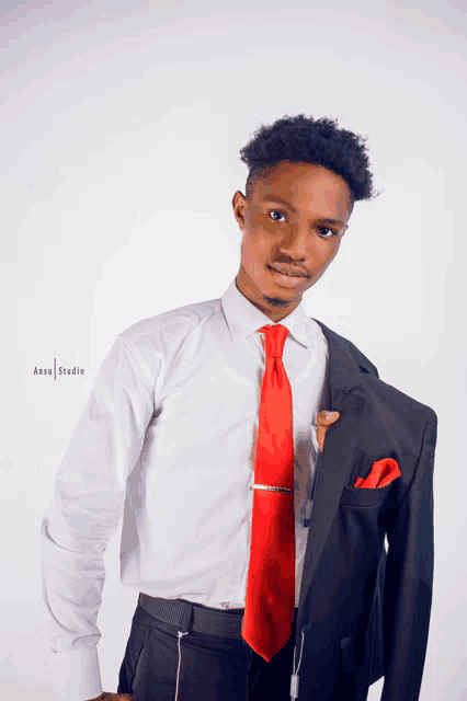 a man in a white shirt and red tie holds his jacket over his shoulder with a photo taken by anzu studio