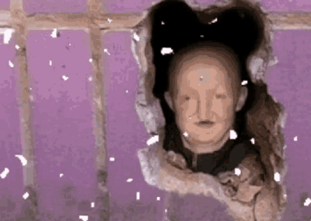 a statue of a bald man is sticking his head out of a hole in the wall .