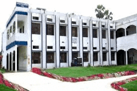 a large white and blue building with a lot of windows is sitting on top of a lush green lawn .