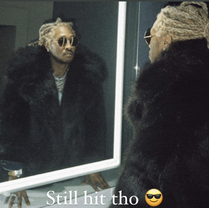 a man in a fur coat is looking at himself in a mirror and the caption says still hit tho