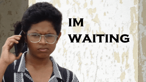 a person talking on a cell phone in front of a sign that says ' im waiting '