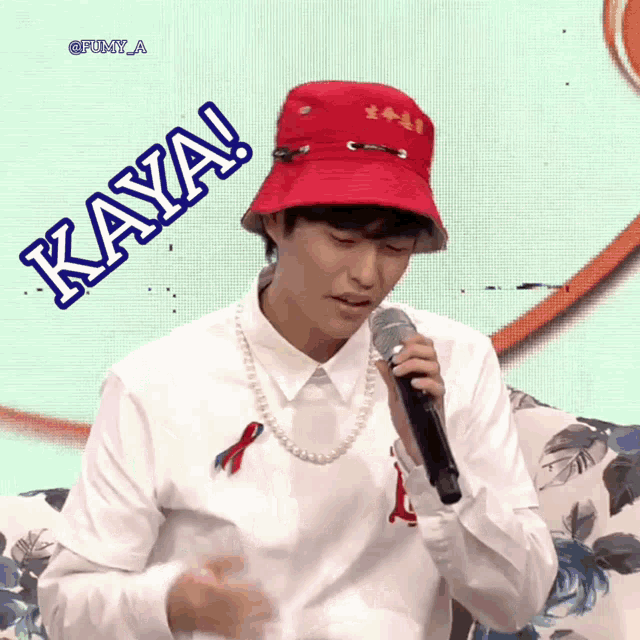 a man wearing a red hat and a white shirt is singing into a microphone with the word kaya behind him