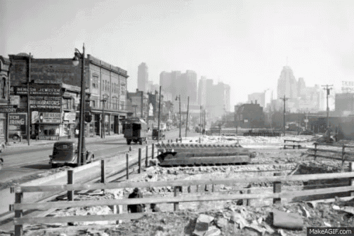 a black and white photo of a city street with a fence in the foreground and a sign that says new ring