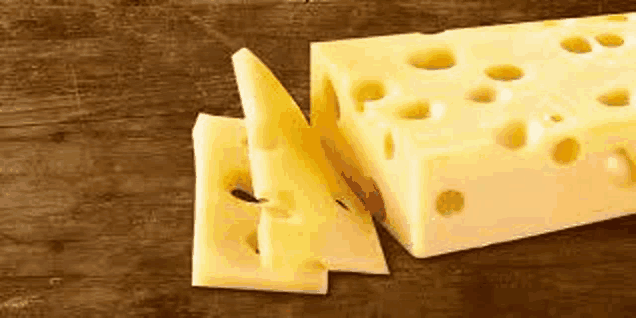 a piece of cheese is sitting on top of a wooden table .