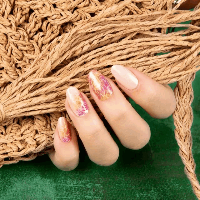 a close up of a woman 's nails with a crocheted bag in the background