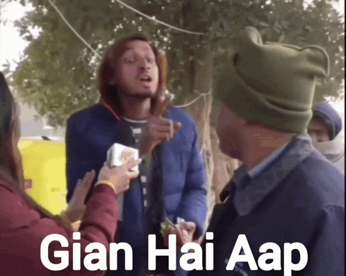 a man wearing a green hat is talking to a woman who is holding a piece of paper that says gian hai aap on it