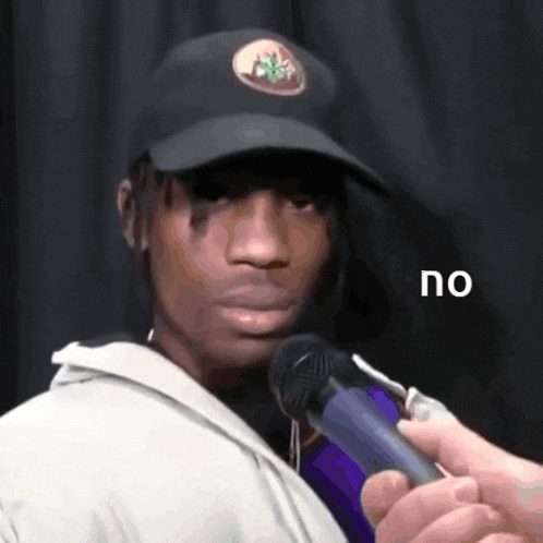 a man wearing a hat is holding a microphone and says " no "