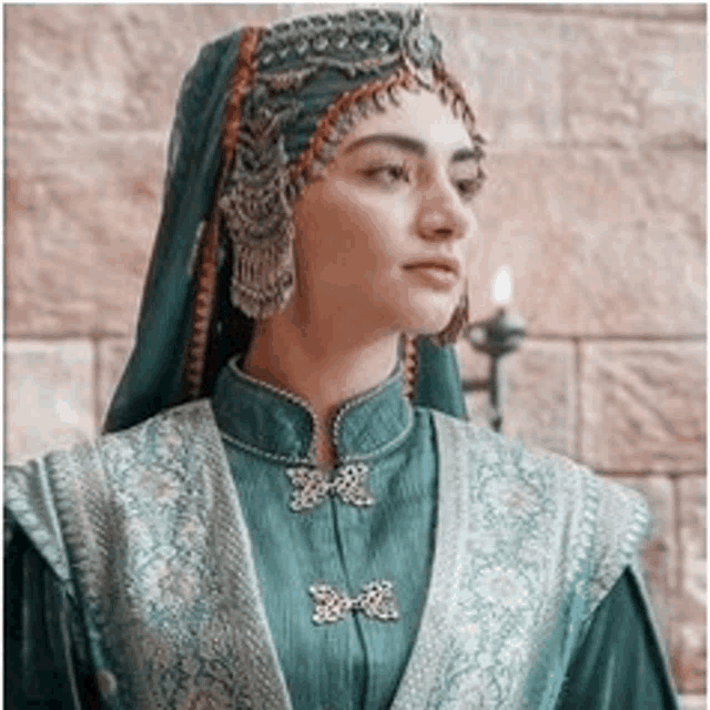 a woman in a traditional costume is wearing a veil and earrings .