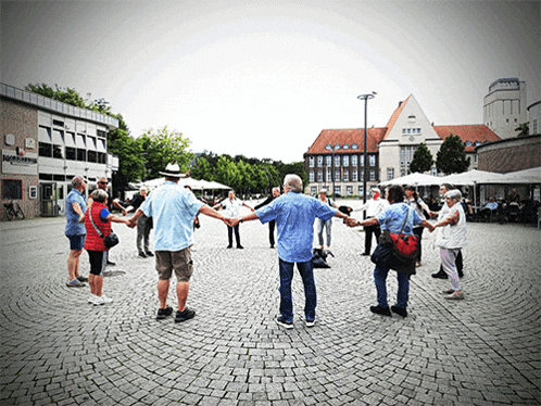 a group of people are standing in a circle holding hands in front of a building that says ' magic hotel '