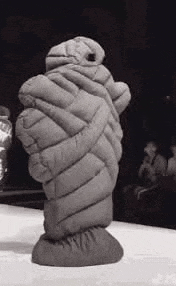 a black and white photo of a statue wrapped in a blanket on a stage .