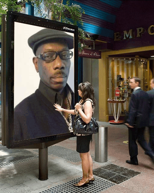 a woman stands in front of a billboard with a picture of a man on it that says jcdecaux