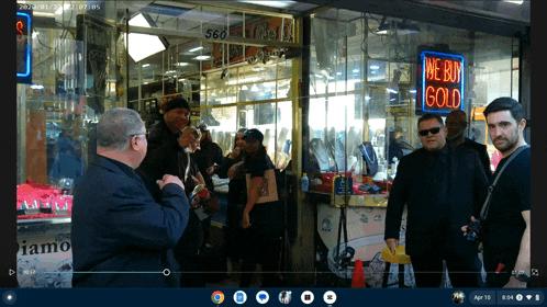 a group of people standing in front of a store with a neon sign that says we buy gold