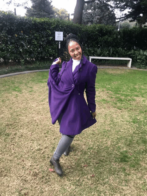 a woman in a purple coat stands in front of a sign that says no dogs