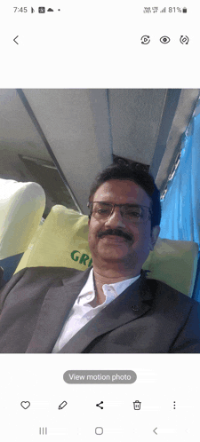 a man in a suit is sitting on a bus with a green pillow