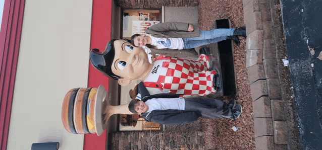 two people standing in front of a statue of big boy