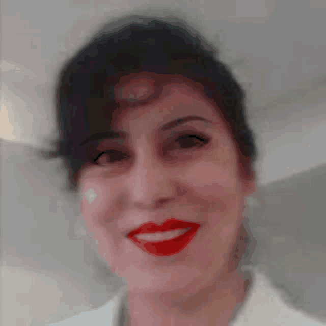 a woman wearing red lipstick and a white shirt smiles for the camera .