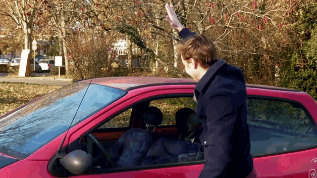 a man stands in front of a red car with a sticker on the side that says ' t '