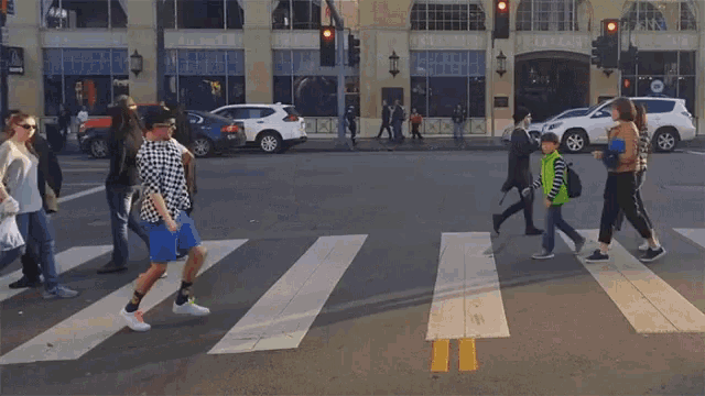 a group of people are crossing a street in front of a building that says ' embassy ' on it