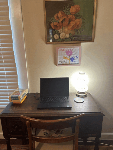 a laptop sits on a desk under a painting that says love on it