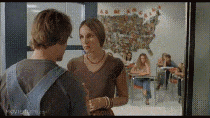 a man and a woman are talking in a classroom with a map of the united states in the background .