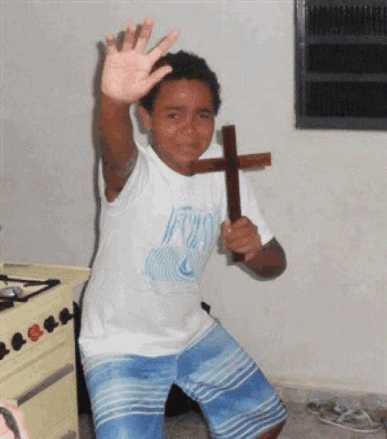 a young boy is holding a wooden cross in his hand