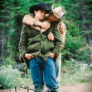 a man in a cowboy hat is hugging another man .